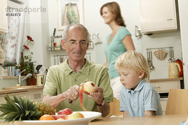 Opa schält Apfel für Enkel  junge Frau im Hintergrund