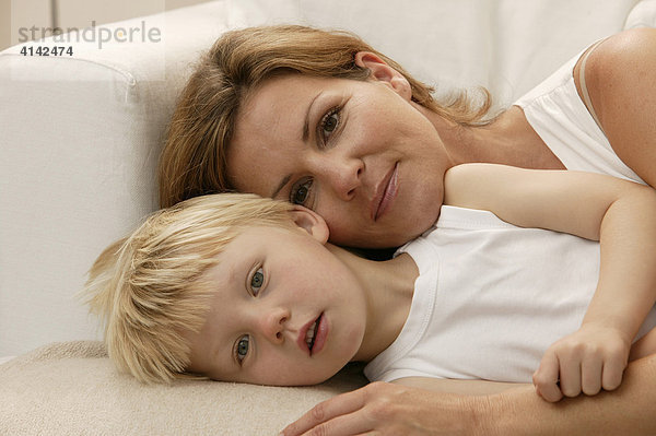 Mutter und Sohn kuscheln auf der Couch  Blick in Kamera