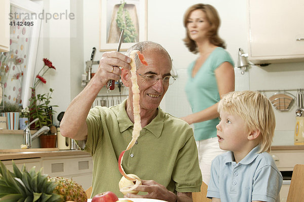 Opa schneidet Apfel für Enkel  Frau unscharf im Hintergrund