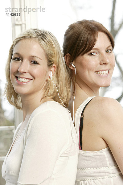 Zwei junge Frauen hören Musik mit einem paar Ohrhörer