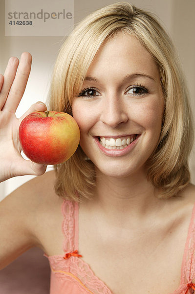 Junge  blonde Frau mit Apfel  lächelt