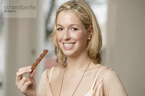 Junge  blonde Frau mit Schokolade  lächelt