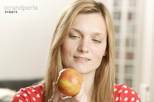 Blonde Frau sieht Apfel an