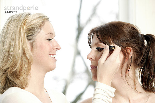 Blonde  junge Frau Frau schminkt ihre Freundin