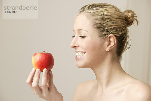 Junge  blonde Frau mit Apfel  lächelnd