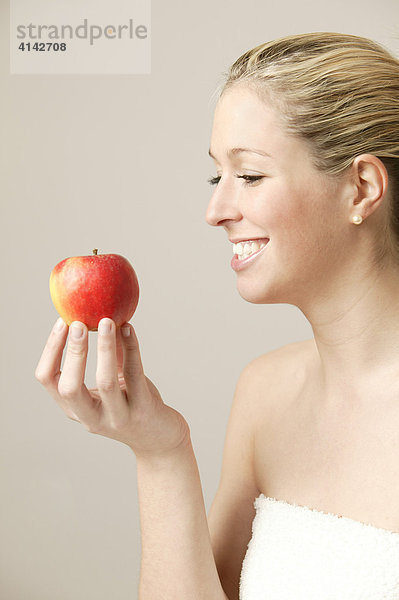 Junge  blonde Frau mit Apfel  lächelnd