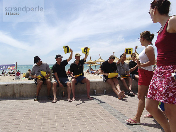 ESP  Spanien  Balearen  Mallorca : Badestrand bei S'Arenal  Ballermann  Bucht von Palma. Touristenstrand. Deutsche Touristen bewerten  als Gag  vorbei laufende Frauen mit Punktevergabe.