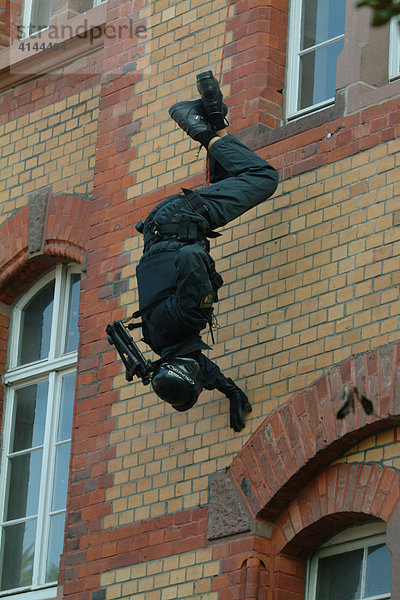 DEU  Deutschland: SEK-Beamter seilt sich kopfueber ab  um in ein Fenster zu spaehen  in dem sich ein Taeter befinden soll. Spezialeinsatzkommando  SEK. Wird zur Verhaftung gefaehrlicher Taeter eingesetzt. Bei Geiselbefreiungen aus Banken  Haeusern  Bussen  Zuegen  Flugzeugen  Schiffen  Fahrzeugen aller Art. Sie verhaften Erpresser  Drogenhaendler  Straftaeter aus dem Bereich der organisierten Kriminalitaet. Sie ueberwaeltigen bewaffnete  gewaltbereite Personen bei Bedrohungslagen. Sie haben eine besondere Ausbildung und umfangreiche Ausruestung und Bewaffnung.