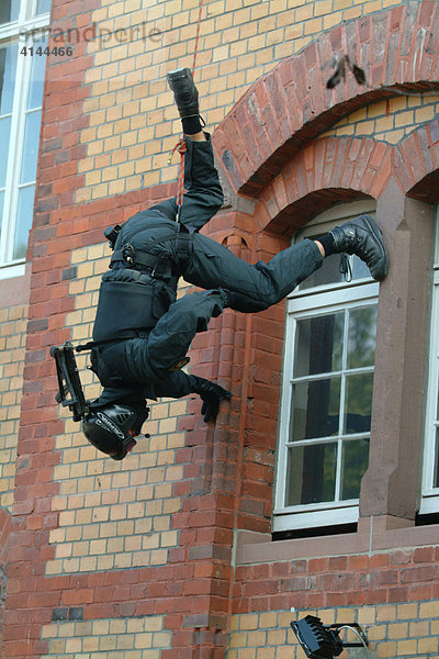 DEU  Deutschland: SEK-Beamter seilt sich kopfueber ab  um in ein Fenster zu spaehen  in dem sich ein Taeter befinden soll. Spezialeinsatzkommando  SEK. Wird zur Verhaftung gefaehrlicher Taeter eingesetzt. Bei Geiselbefreiungen aus Banken  Haeusern  Bussen  Zuegen  Flugzeugen  Schiffen  Fahrzeugen aller Art. Sie verhaften Erpresser  Drogenhaendler  Straftaeter aus dem Bereich der organisierten Kriminalitaet. Sie ueberwaeltigen bewaffnete  gewaltbereite Personen bei Bedrohungslagen. Sie haben eine besondere Ausbildung und umfangreiche Ausruestung und Bewaffnung.