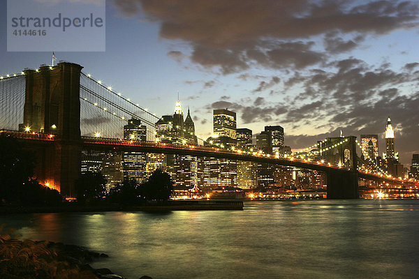 USA  Vereinigte Staaten von Amerika  New York City: Skyline von Sued-Manhattan  Financial District  in der Daemmerung  von Brooklyn aus gesehen. Brooklyn Bridge  East River.