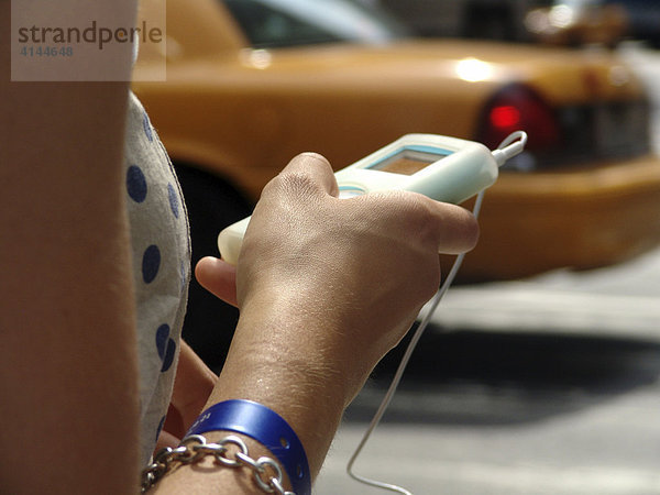 USA  Vereinigte Staaten von Amerika  New York City: Frau traegt ihren Apple iPod auf der Strasse mit sich und hoert Musik.