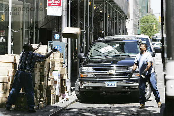 USA  Vereinigte Staaten von Amerika  New York City: Lieferwagen bringt Waren zu einem Geschaeft. Personal wirft sich die Pakte zu.