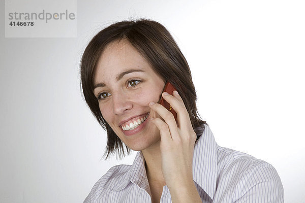 Junge Frau telefoniert lächelnd mit dem Handy