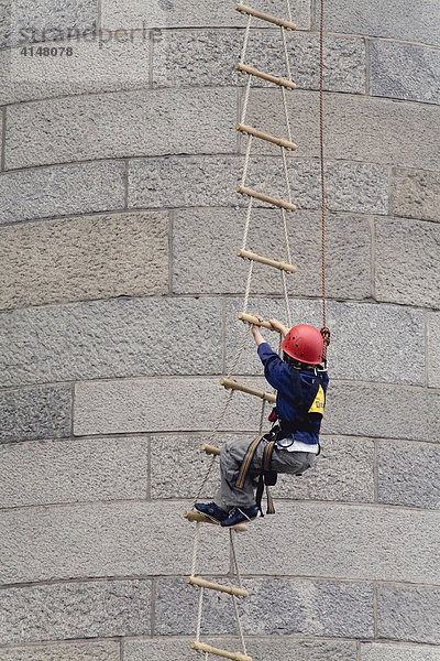 Kleiner Junge mit rotem Schutzhelm klettert eine Strickleiter hoch  Deutschland