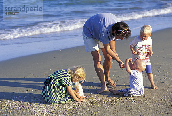 Mutter mit Kindern sammelt am Strand Muscheln
