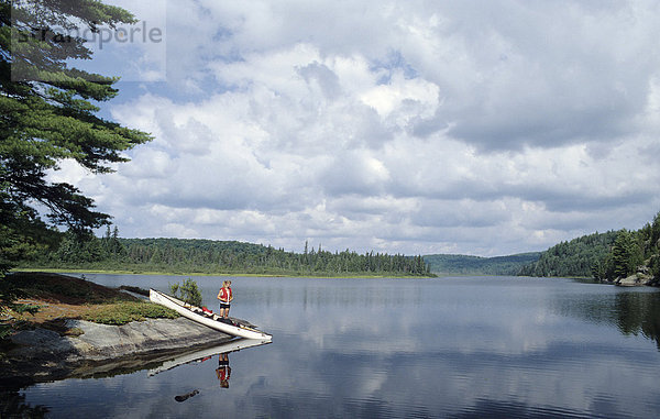 Junge Frau mit Kanu an einem See im Algonquin Provincial Park  Kanada
