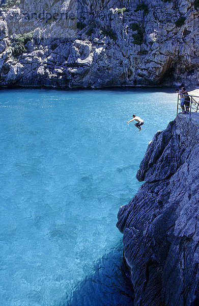 Junger Mann springt von einem Felsen ins Meer bei Sa Calobra auf Mallorca  Spanien