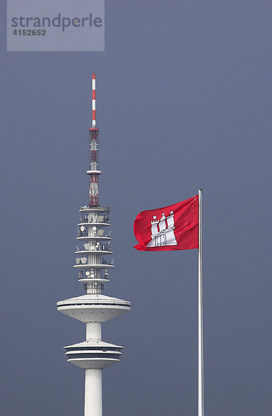 Eine Flagge mit dem Stadtwappen von Hamburg weht vor dem Fernsehturm in Hamburg