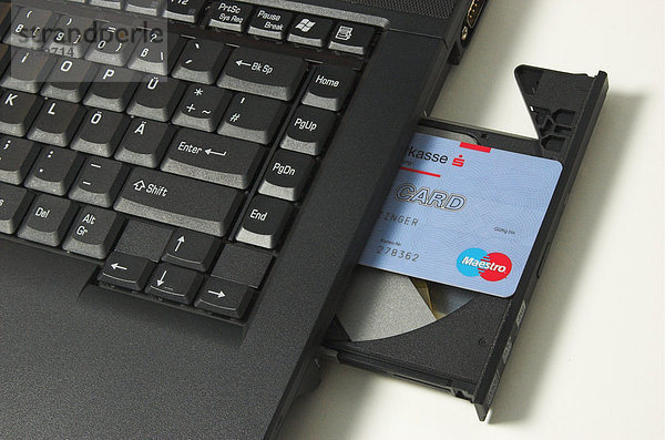 Online Banking  eine ec-Karte ragt aus dem CD-Laufwerk eines Notebook Computers