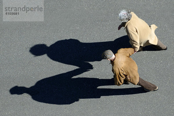 Älteres Ehepaar geht Hand in Hand spazieren  Aufnahme aus der Vogelperspektive mit Schattenwurf