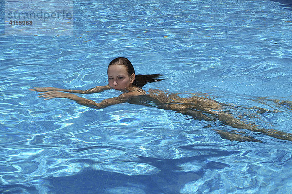 Junge Frau schwimmt ohne Badekleidung im Swimmingpool einer spanischen Finca  Mallorca  Spanien
