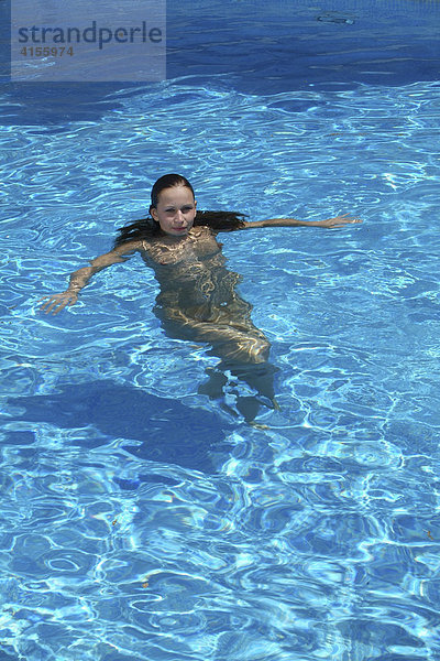 Junge Frau schwimmt ohne Badekleidung im Swimmingpool einer spanischen Finca  Mallorca  Spanien
