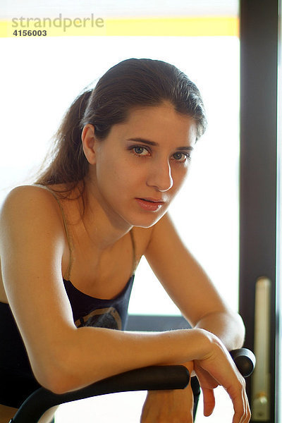 Portrait einer jungen Frau beim Sport auf einem Hometrainer