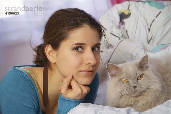 Junge Frau mit ihrer Katze auf dem Bett
