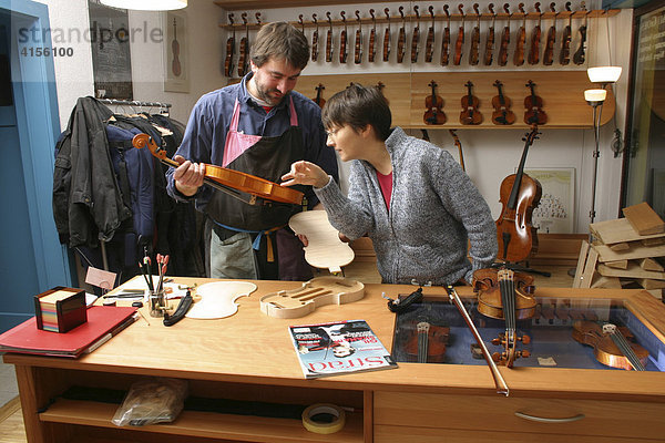 Geigenbauer mit Kundin im Verkaufsraum