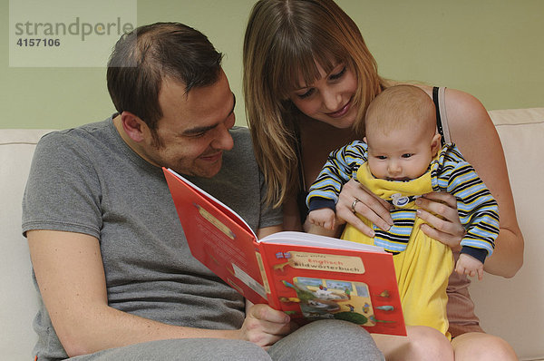 Vater  Frau und Baby sehen sich Bildwörterbuch an