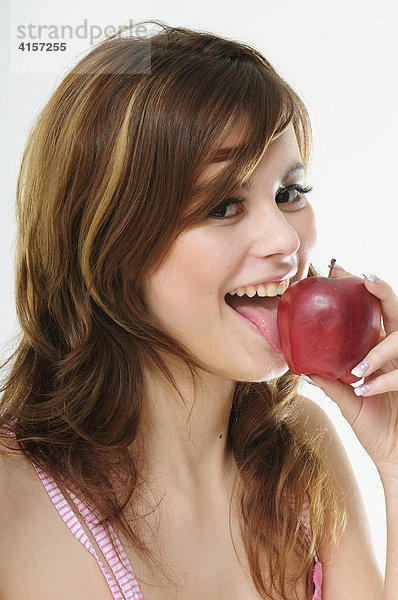 Hübsche junge braunhaarige Frau beißt in einen roten Apfel