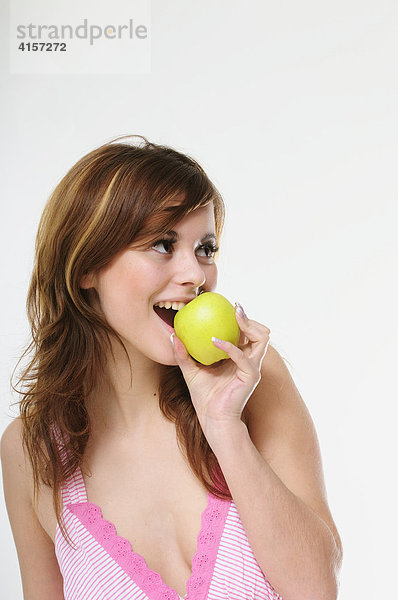 Hübsche junge braunhaarige Frau isst einen grünen Apfel