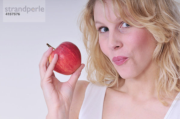 Blonde Frau isst roten Apfel