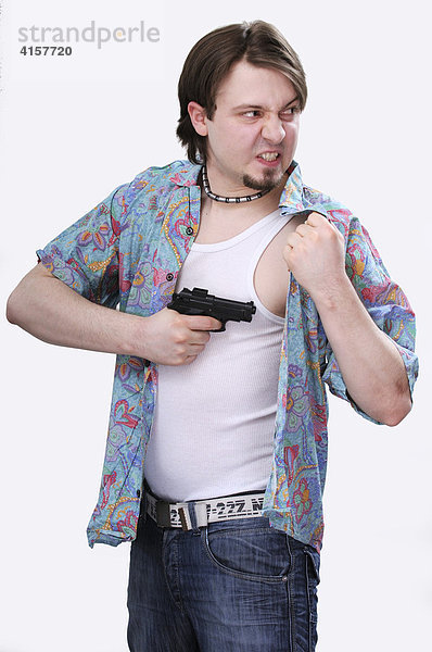 Junger Mann mit Kinnbart in Unterhemd und offenem Oberhemd mit Pistole