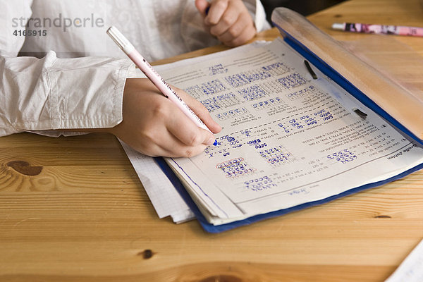 Junge Schülerin lernt im Kinderzimmer für die Schule und schreibt Rechenaufgaben