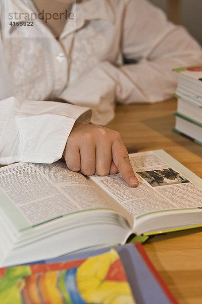 Junge Schülerin liest in einem Buch im Kinderzimmer für die Schule