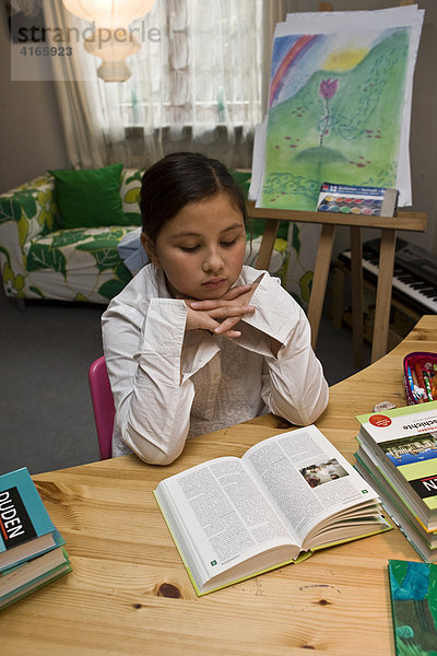 Junge Schülerin liest in einem Buch im Kinderzimmer für die Schule und überlegt