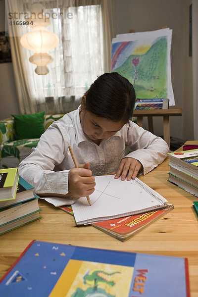 Junge Schülerin malt wütend in ein Heft für die Schule
