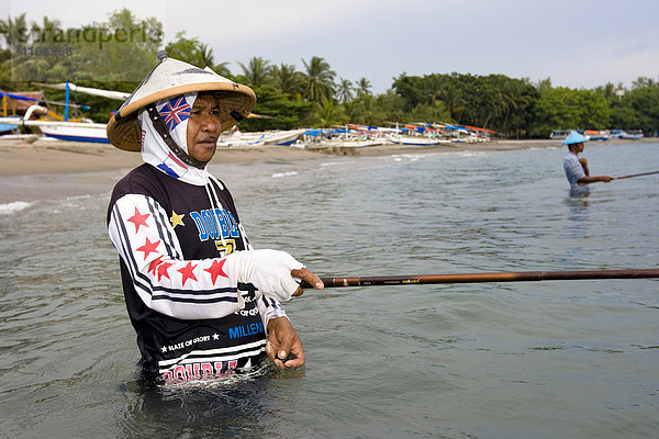 Alter Mann steht im Meer bei Senggigi und angelt in traditioneller Weise kleine Fische  Insel Lombok  Kleine-Sunda-Inseln  Indonesien