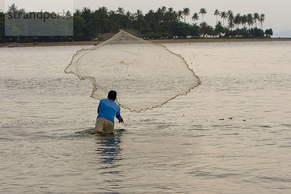 Fischer wirft sein Netz am Abend in einer Bucht aus  Insel Lombok  Kleine-Sunda-Inseln  Indonesien