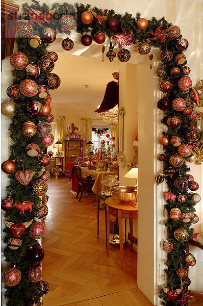 Weihnachtsdeko um eine Tür vom Wintergarten in das Wohnzimmer  bunter Weihnachtsschmuck an einem Tannenzweig um eine Tür dekoriert