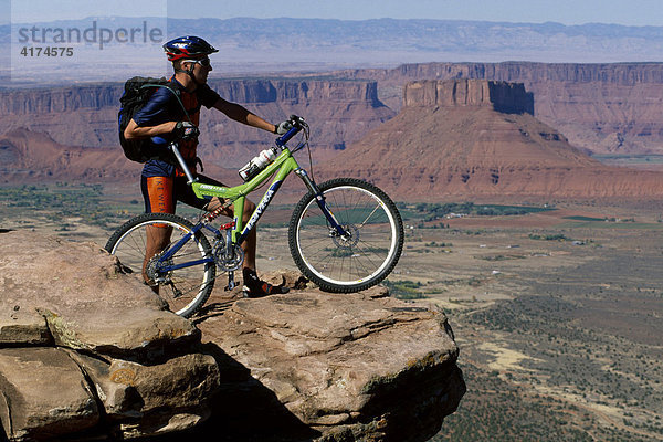 Mountainbiker auf einem Felsen über dem Canyon  Moab  Utah  USA
