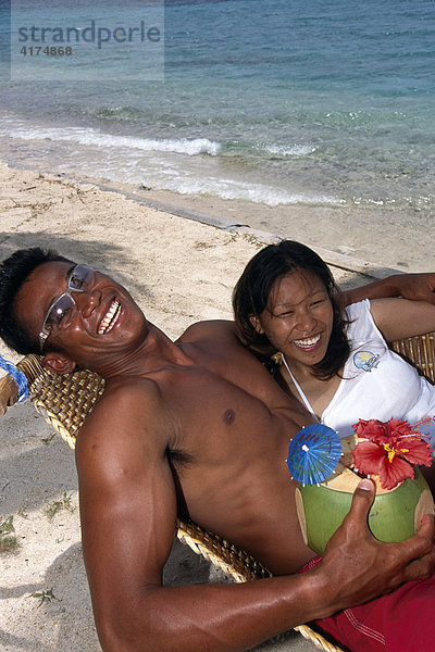 Filipinos am Strand mit einem Früchtedrink