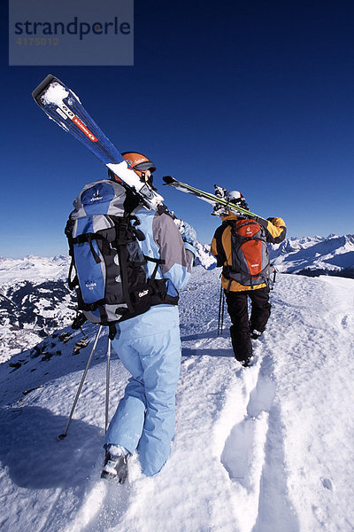 Skifahrer tragen ihre Skier hoch