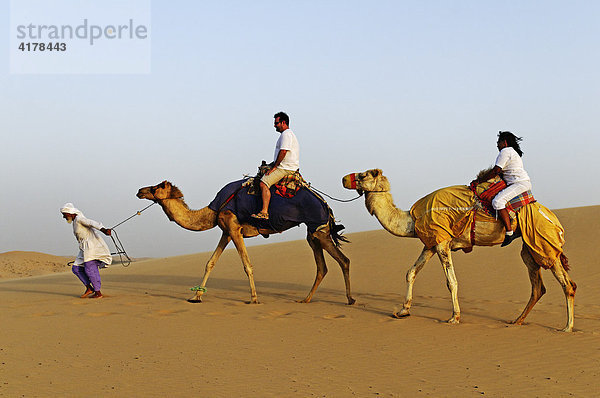 Beduine führt Kamele mit Touristen bei einer Wüstentour im Emirat Abu Dhabi  Vereinigte Arabische Emirate  VAE  Asien
