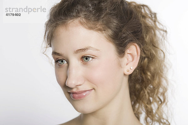 Lachende junge Frau mit gelockten Haaren im Halbprofil vor weißem Hintergrund