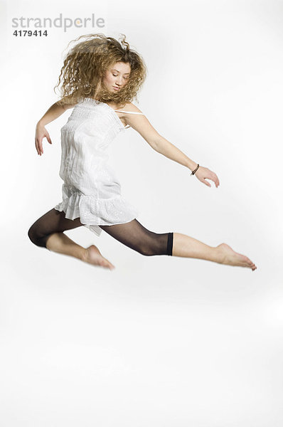 Junge Frau springt vor weißem Hintergrund