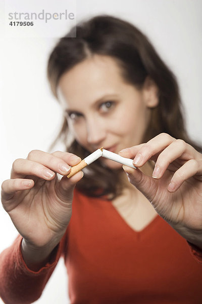 Junge Frau bricht eine Zigarette durch
