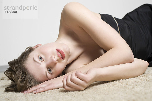 Portrait einer jungen  auf einem Teppich liegenden Frau