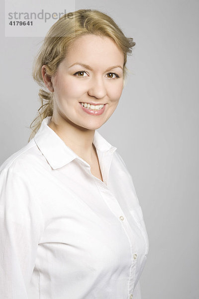 Portrait einer jungen blonden Frau in weißer Bluse  lachend
